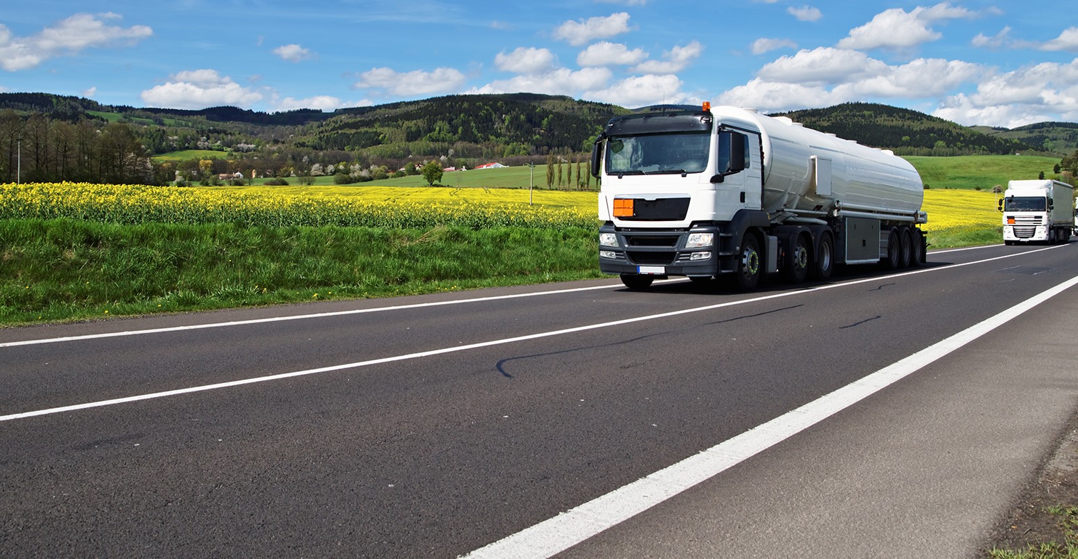 Biofuel trucks driving along a rapeseed field.