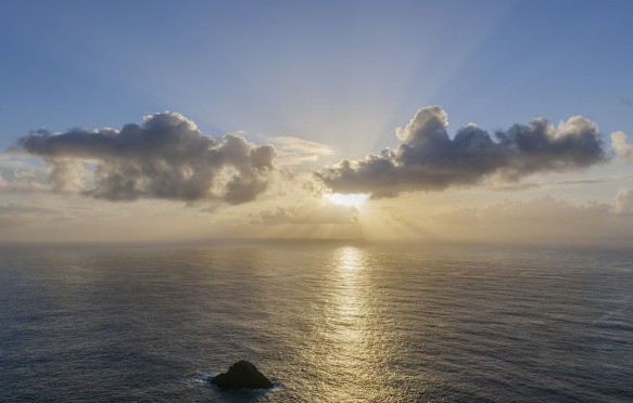 Evening sun behind clouds above the sea, Shetland Islands.