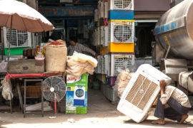 An air conditioning vendor prepares a unit for sale in Delhi, India. Credit: Kevin Su / Alamy Stock Photo.