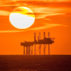 Sunset pours into the horizon behind the Hamilton Oil Rig off the Southport coastline, UK