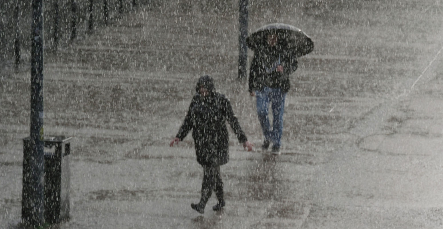 Two people hurry along the Southbank in London as torrential downpour continues