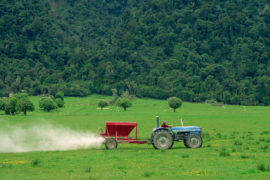 Farmer spraying fertiliser on a field for sheep grazing in New Zealand