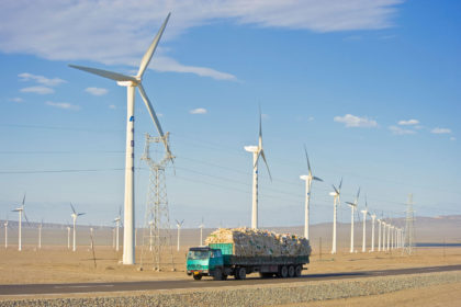 A truck travelling along the G30 Lianhuo expressway with part of the Daheyan wind farm in the background in Xinjiang, China. Credit: Paul Springett D / Alamy Stock Photo