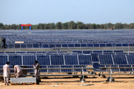 Workers install solar photovoltaic panels in Pakistan.