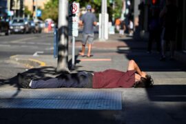 A man lies on a sidewalk during a heatwave in Portland, Oregon, U.S, on 11 August 2021.