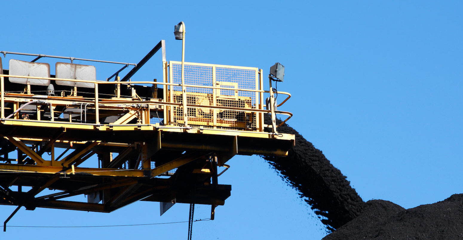 Yellow coal Conveyor belt carrying coal and pouring onto a pile in Australia.