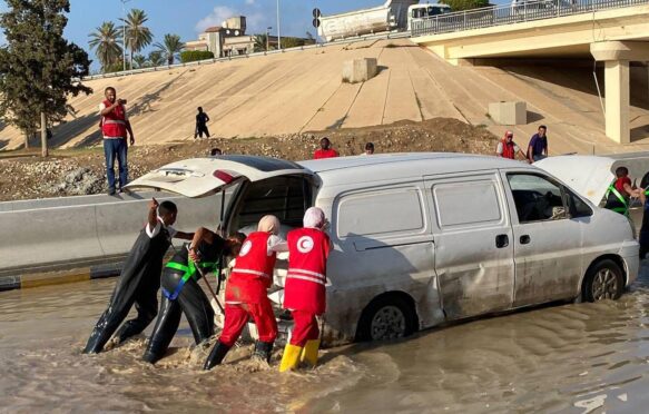 Libyan Red Crescent members work on opening roads engulfed in floods.