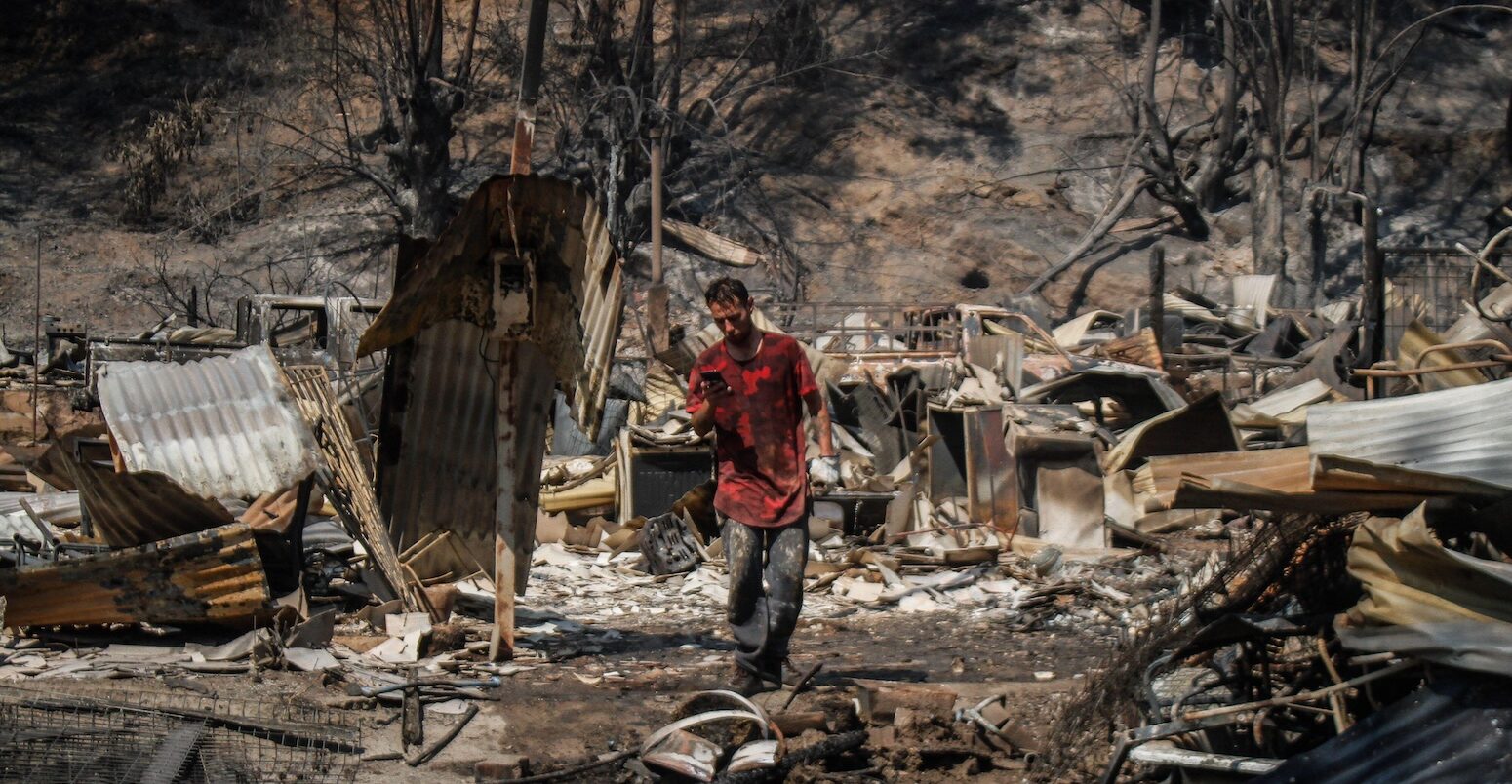 A person standing among the rubble from the Chilean “megafires”.