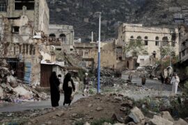 People walk on the rubble of houses destroyed by war in Taiz, Yemen.