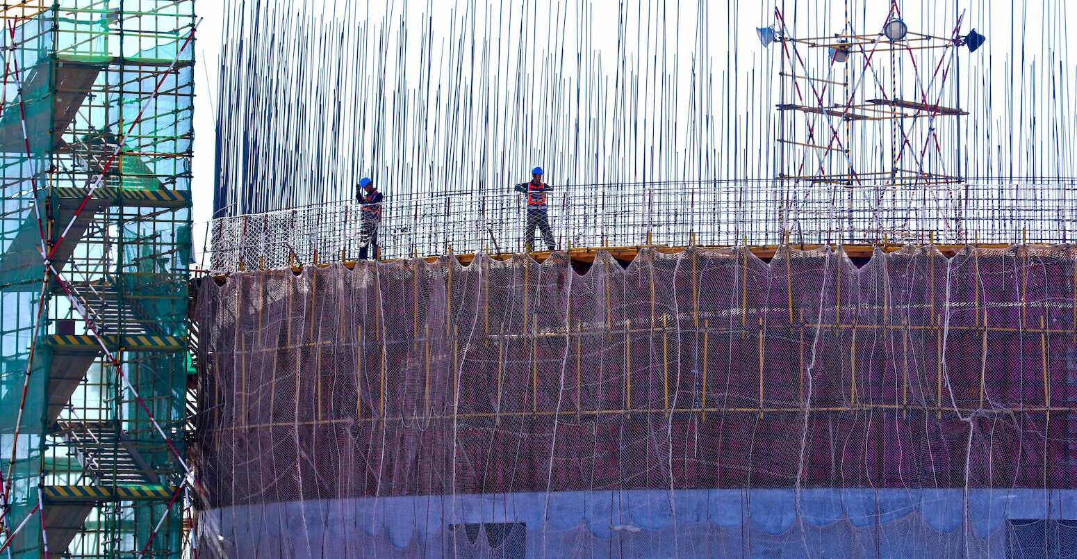 Builders bundle steel frames at a coal construction site in Gansu, China.