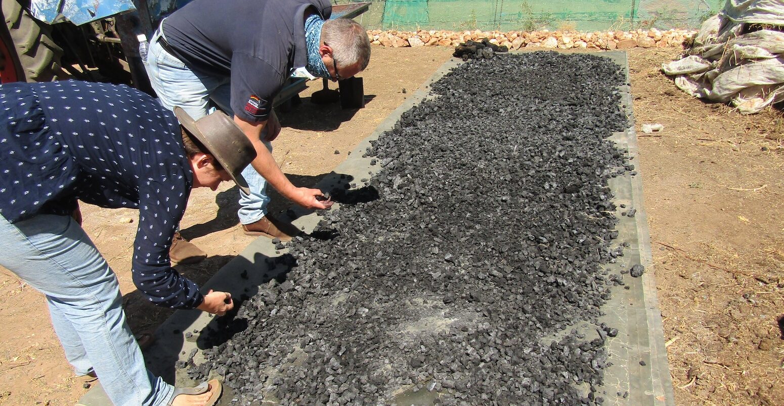 People check semi-processed biochar at a farm near Windhoek, Namibia.