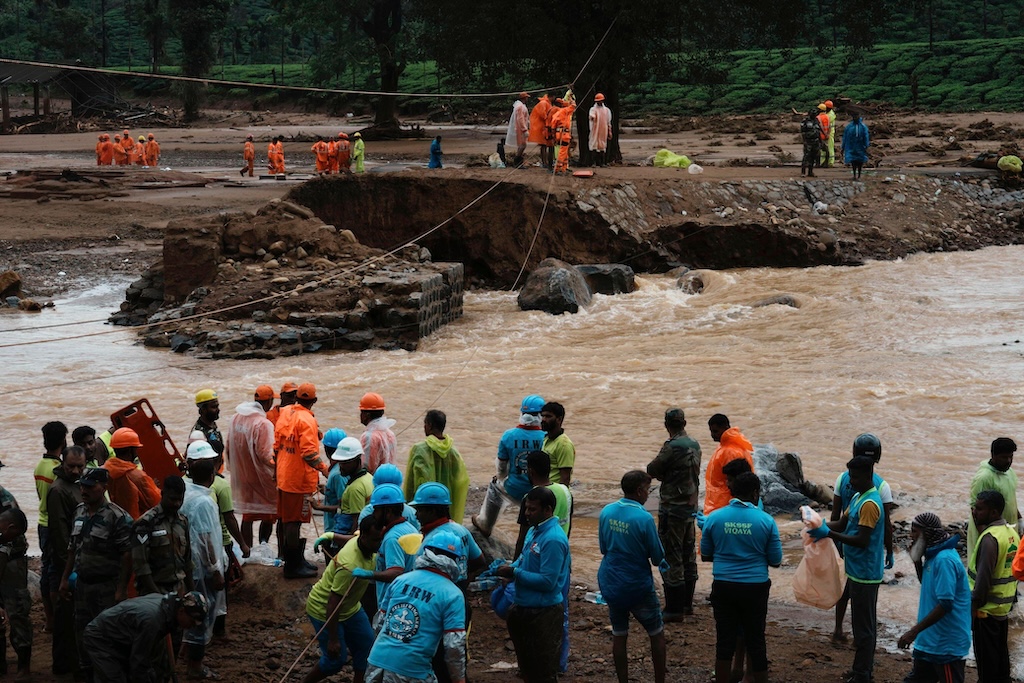 Rescuers wait to cross a river in Kerala state, India after a landslide on 31 July 2024.