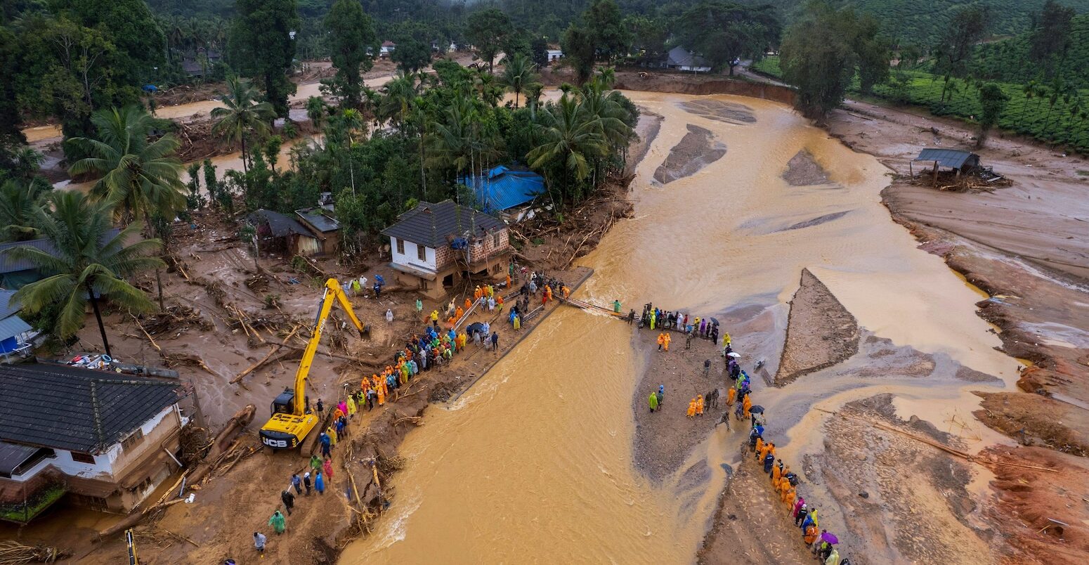 Rescuers cross a river in Kerala state, India after a landslide on 31 July 2024.