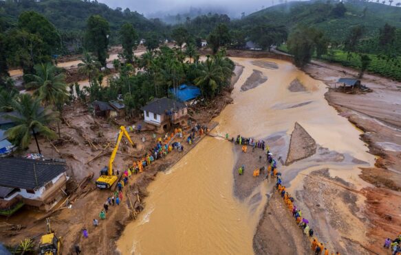 Rescuers cross a river in Kerala state, India after a landslide on 31 July 2024.