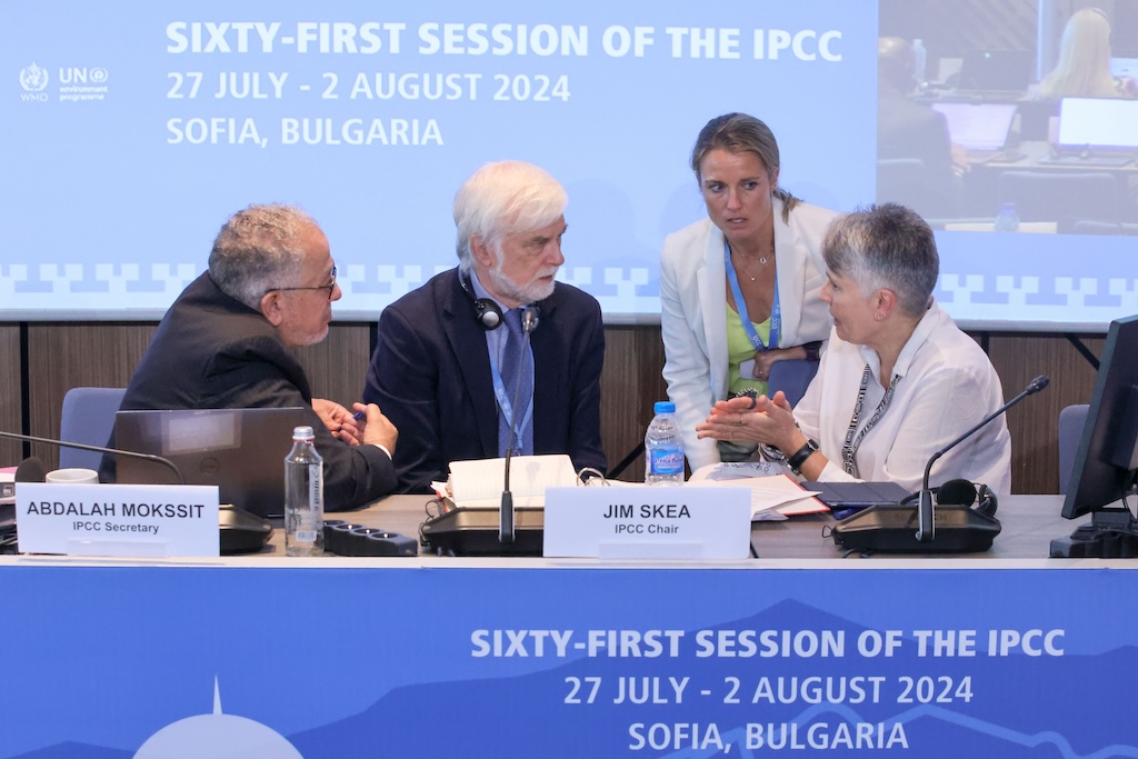 IPCC secretary Abdalah Mokssit and IPCC chair Jim Skea consult with Brittany Croll, US, and Debra Roberts, South Africa, on 27 July. Photo by IISD/ENB | Anastasia Rodopoulou