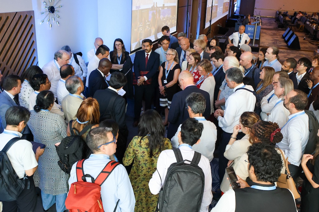 IPCC delegates convene in a huddle at the end of the afternoon plenary session on 29 July. Photo by IISD/ENB | Anastasia Rodopoulou