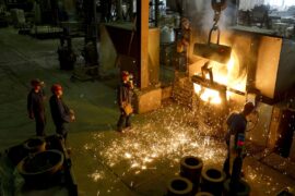 Workers racking the blast furnace in a foundry.