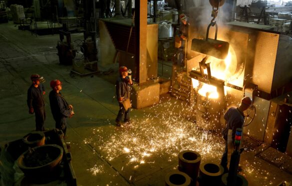 Workers racking the blast furnace in a foundry.