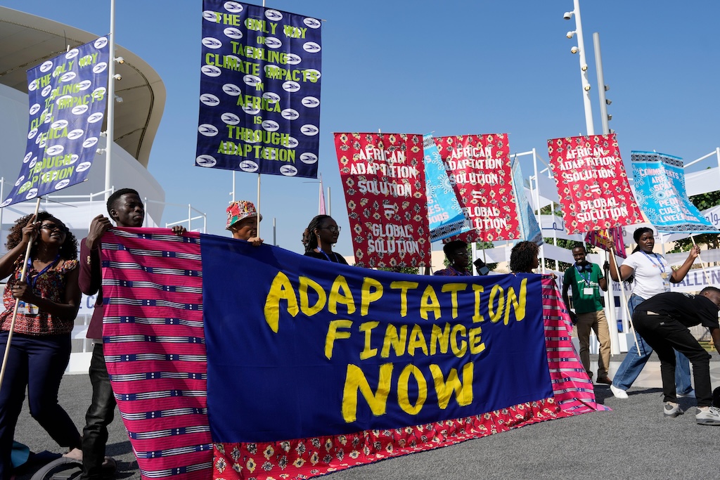 Activists participate in a demonstration with a sign that reads "adaptation finance now" at COP28 in Dubai, UAE.