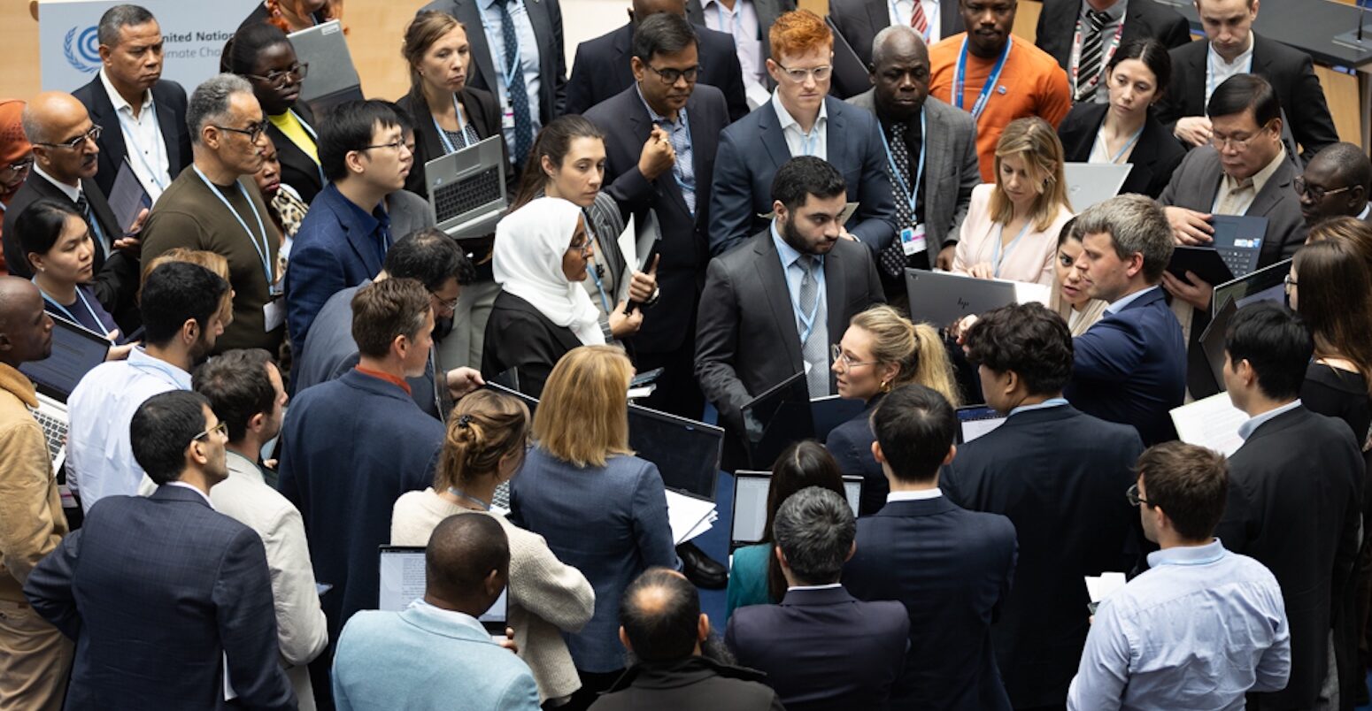 Delegates huddle during consultations on Paris Agreement Article 6.8.