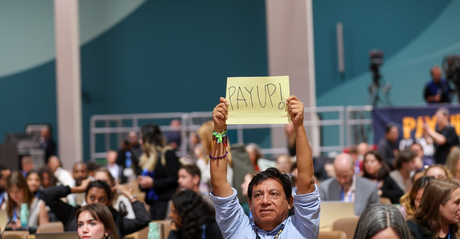 A man holds up a 'pay-up' sign at COP29 in Baku.