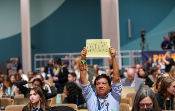 A man holds up a 'pay-up' sign at COP29 in Baku.