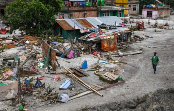 A man walks past flooded houses in the flood affected area along the Teesta River.