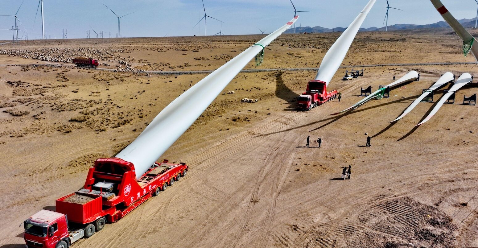 Builders transfer wind turbine blades to a hoisting site at the construction site in Zhangye, China.