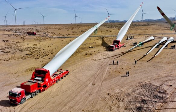 Builders transfer wind turbine blades to a hoisting site at the construction site in Zhangye, China.