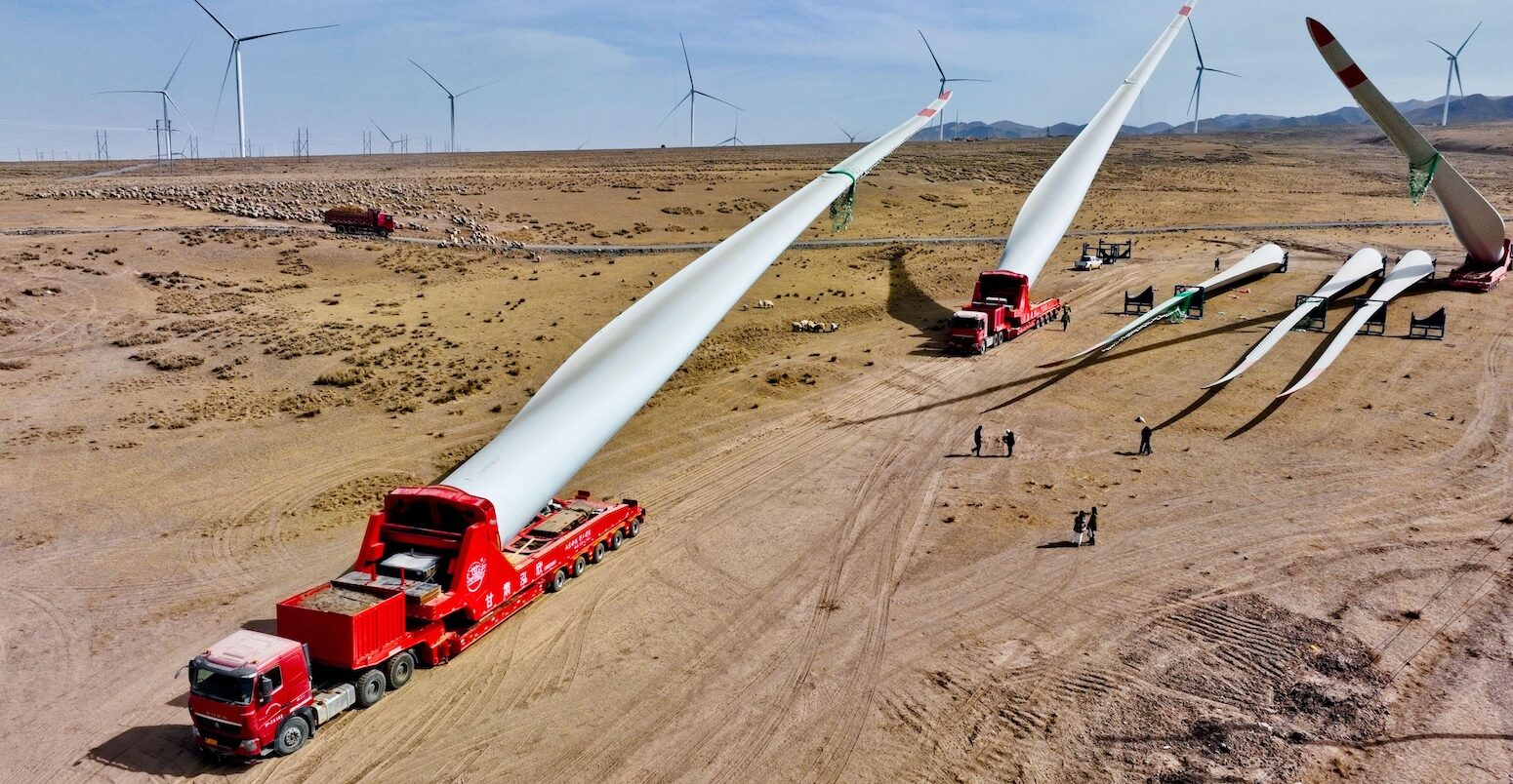 Builders transfer wind turbine blades to a hoisting site at the construction site in Zhangye, China. Credit: Sipa US / Alamy Stock Photo. Image ID: 2PHDHEH.