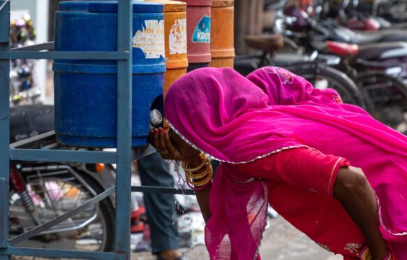 Women drinking water in the street during a heat wave in Rajasthan, India.