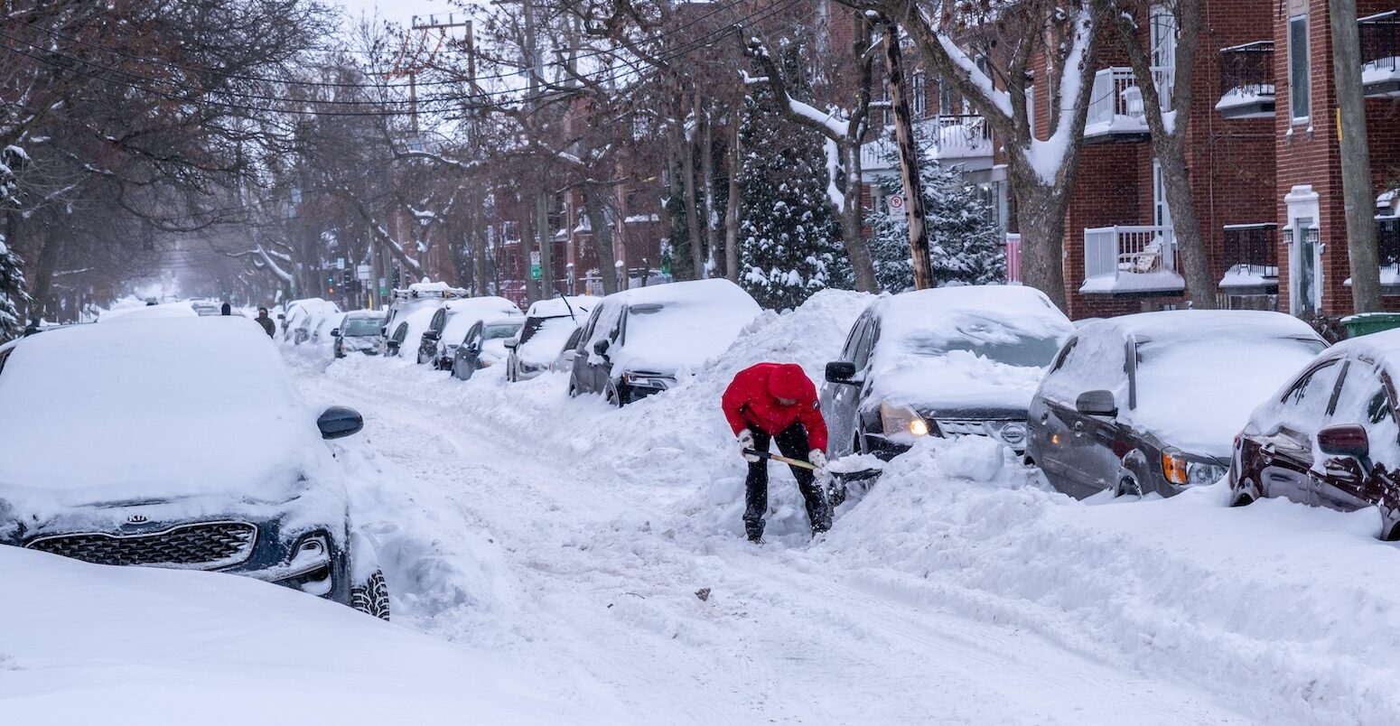 A man shovels snow to free his car after major winter storm in Montreal, Canada.