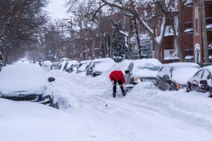 A man shovels snow to free his car after major winter storm in Montreal, Canada.